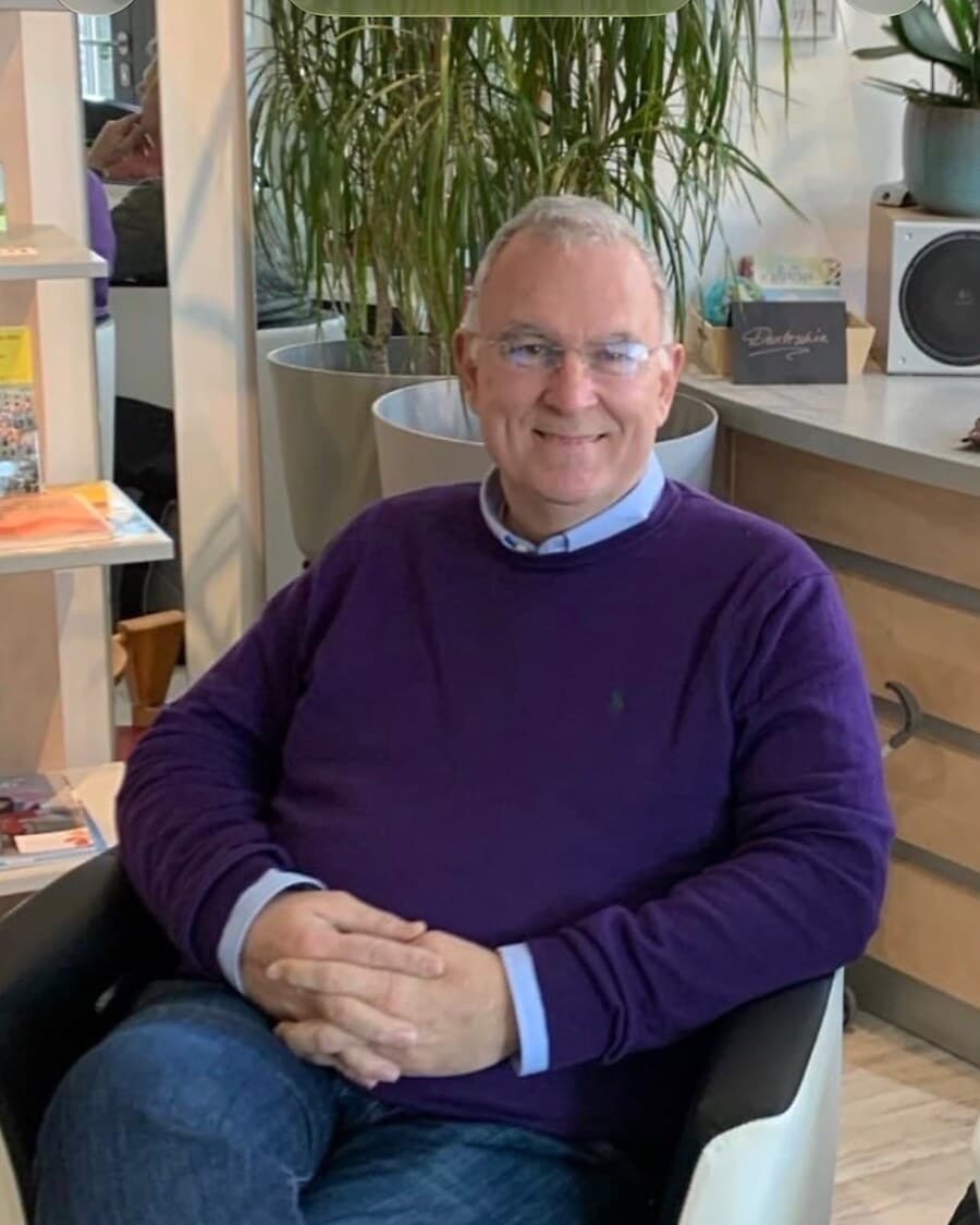Achim aus dem Team der Logopädie in der CoKuK in Kassel – im lila Pullover mit Brille